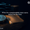 Analog clock beside a nearly empty case file and document trays on a dark desk, illustrating the workers' compensation 120-day rule