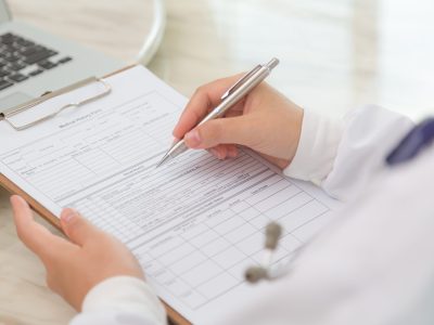 Hand of doctor writing on prescription
